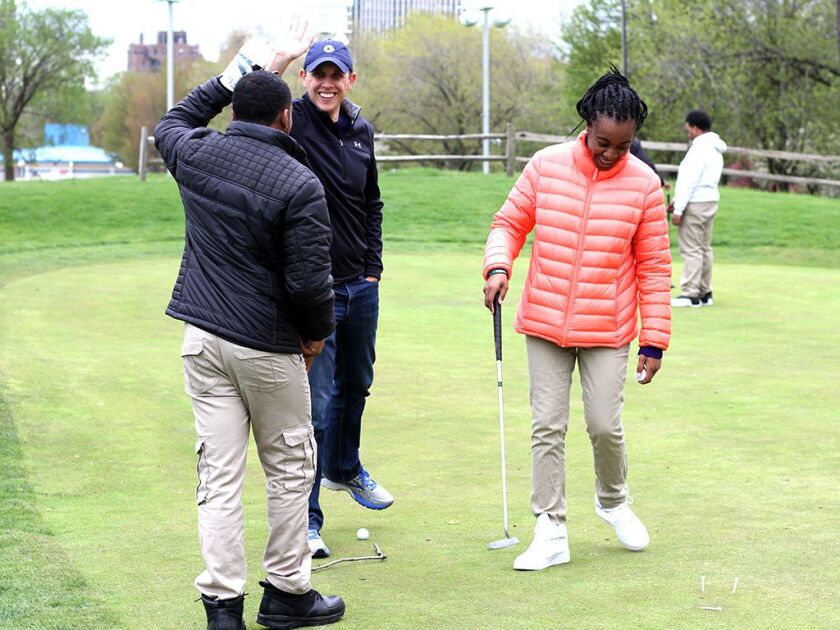 Members of the new golf team at Excel Academy of South Shore get high-fives from Chicago Parks Golf Alliance co-founder and director Michael Ruemmler during practice at South Shore Golf Course. | Photo by Melanie Brown/CPGA