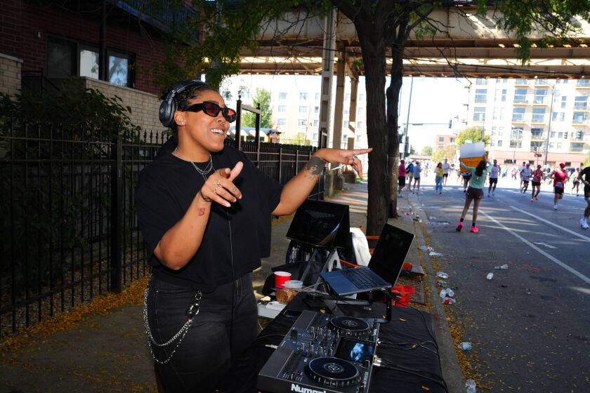 Chloe Wilkerson, 34, stands on 26th Street near Michigan Avenue, giving water and support to runners as they pass by Mile 22 of the 26.-2-mile Chicago Marathon.