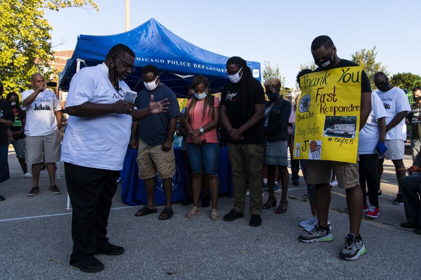 The Shorter family and neighborhood residents pray at Mamie Till-Mobley Park Friday night. A member of the family, a 12-year-old boy, was wounded in a shooting at the park on Aug. 14.