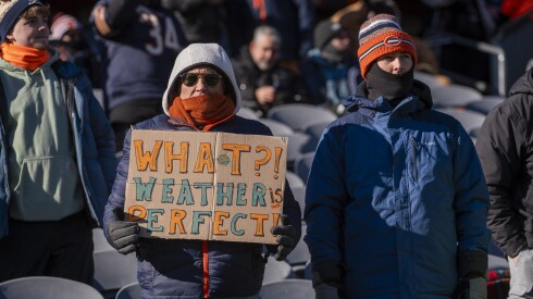 A Chicago Bears fan holds a sign that reads, "What?! Weather is perfect!" at a frigid game in December.