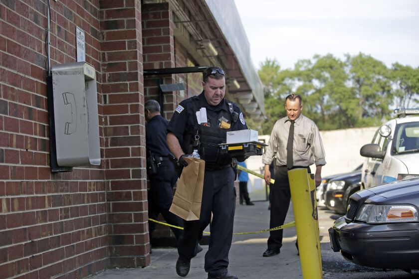 Chicago Police walk outside the Lavanderia Soap Opera Laundromat and Keeler Food & Deli during an investigation of a shooting that killed former basketball player Jonathan Mills in the 4100 Block of West Roosevelt Road on Monday. | Joshua Lott/Getty