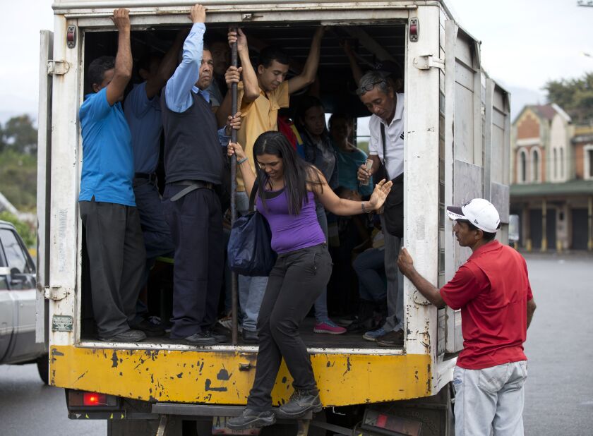 In this Jan. 22, 2018 photo, a woman gets off a cargo truck serving as public transportation in Villa de Cura, Venezuela. Some truck owners prefer to carry passengers instead of merchandise because of looting that targets grain-carrying cargo. | AP photo