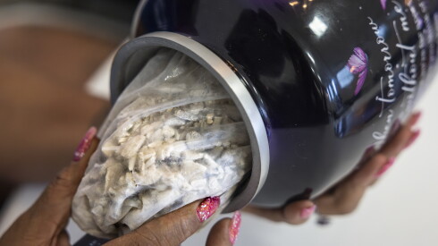 Marshawna Campbell looks at the contents of her mother’s urn during a community forum with attorneys and activists at Genesis Worship Ministry.