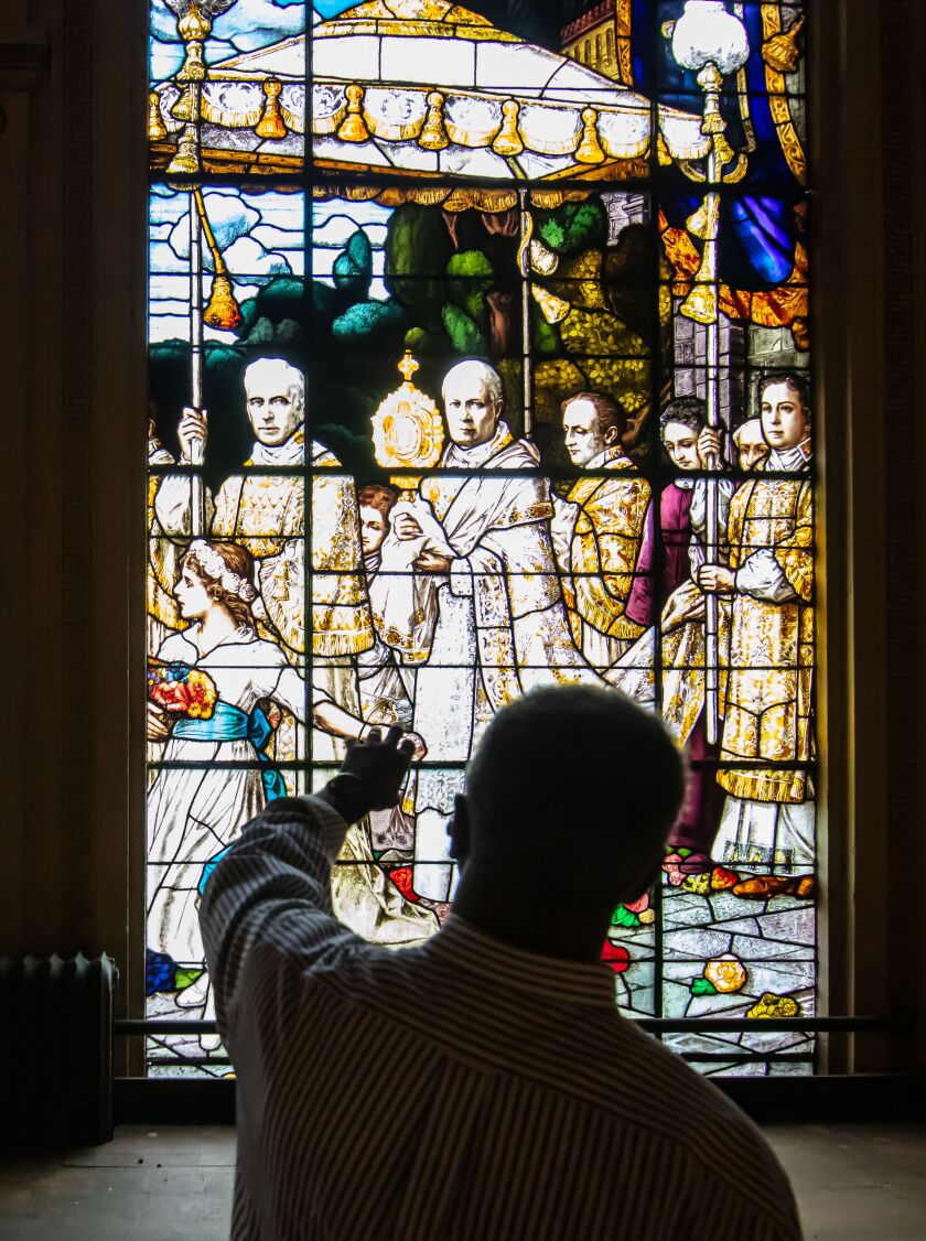 Church historian Larry Cope points out details of the F.X. Zettler-designed stained-glass windows.