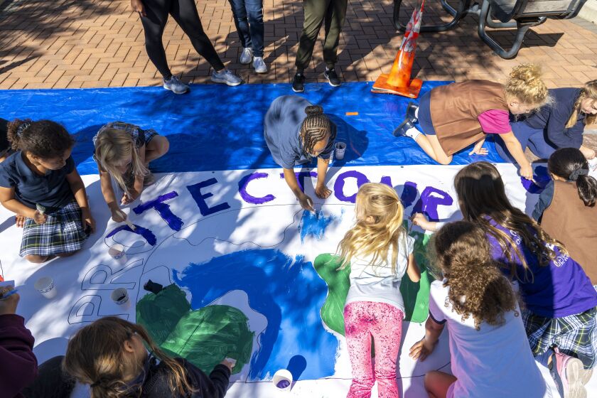 Girl Scouts with Troop 26260 paint as part of a community’s larger protest against the building of a data center at East 21st Street and South Calumet Avenue.