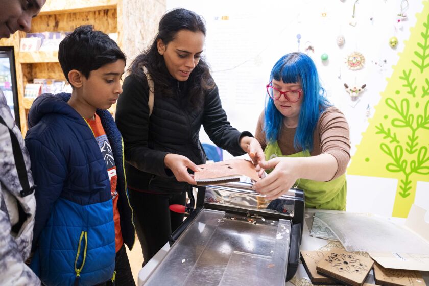 Rebecca Memoli (right), a teaching artist at Creative Chicago Reuse Exchange, guides Joffy Antony Saturday as she makes a paper ornament.