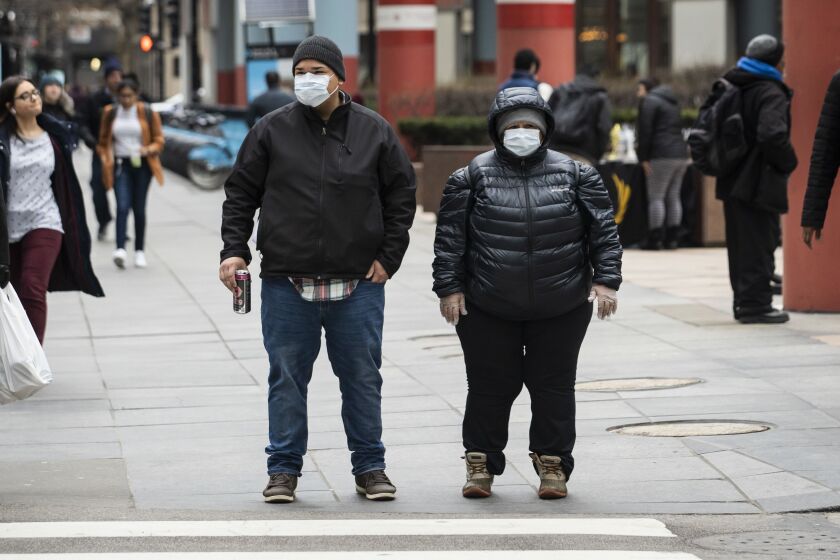A man and woman in the Loop wear face masks Thursday amid growing fear about the coronavirus.