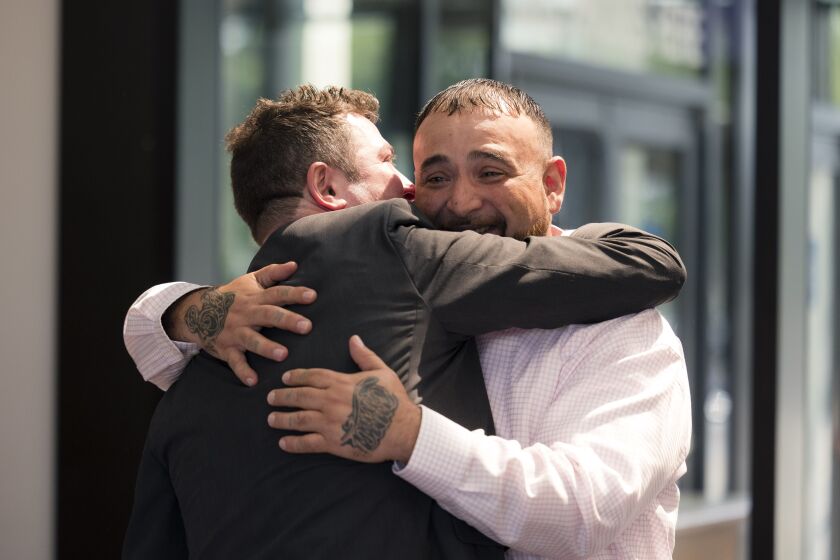 Edgardo Colon, with tears in his eyes, hugs another man.