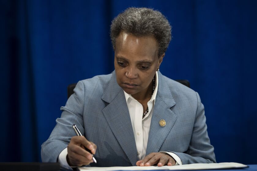 Mayor Lori Lightfoot signs an executive order Tuesday to ensure coronavirus-related benefits offered by the city of Chicago are available to immigrants and refugees.