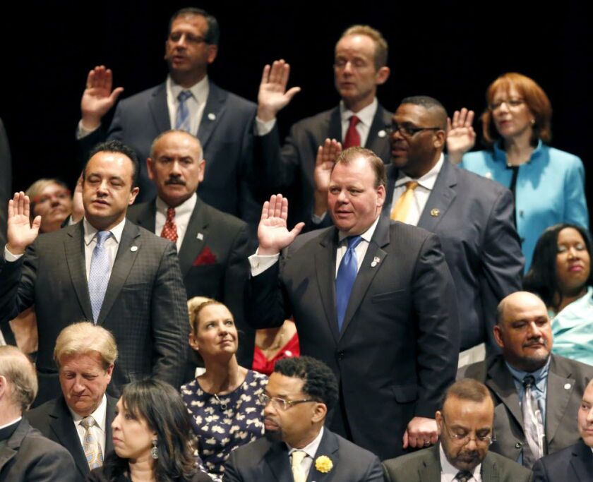 Patrick Daley Thompson, standing front right, takes the oath of office for alderman, while his wife Katie, seated, watches during city government inaugural ceremonies Monday, May 18, 2015, in Chicago. | Charles Rex Arbogast/AP