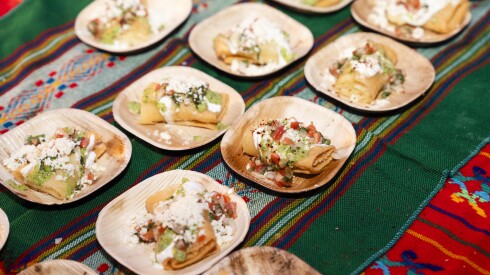 Food is served on small bamboo plates on top of green and red tablecloths