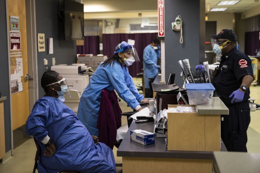 Roseland Community Hospital staffers talk to a Chicago Fire Department EMT in the emergency department last year.