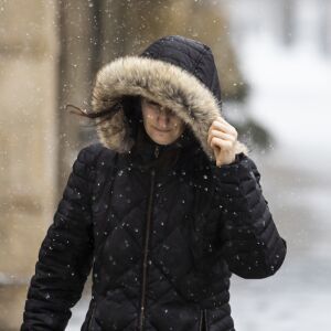 A woman shields her face from the wind on the Near West Side as snow falls on the Chicago area during the morning commute, Wednesday, Feb. 26, 2020.