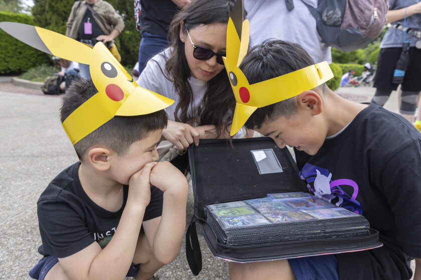Jazgul and sons Aidar and Jomart look at their Pokémon collection while at the Pokémon Go Fest in Grant Park on Friday.