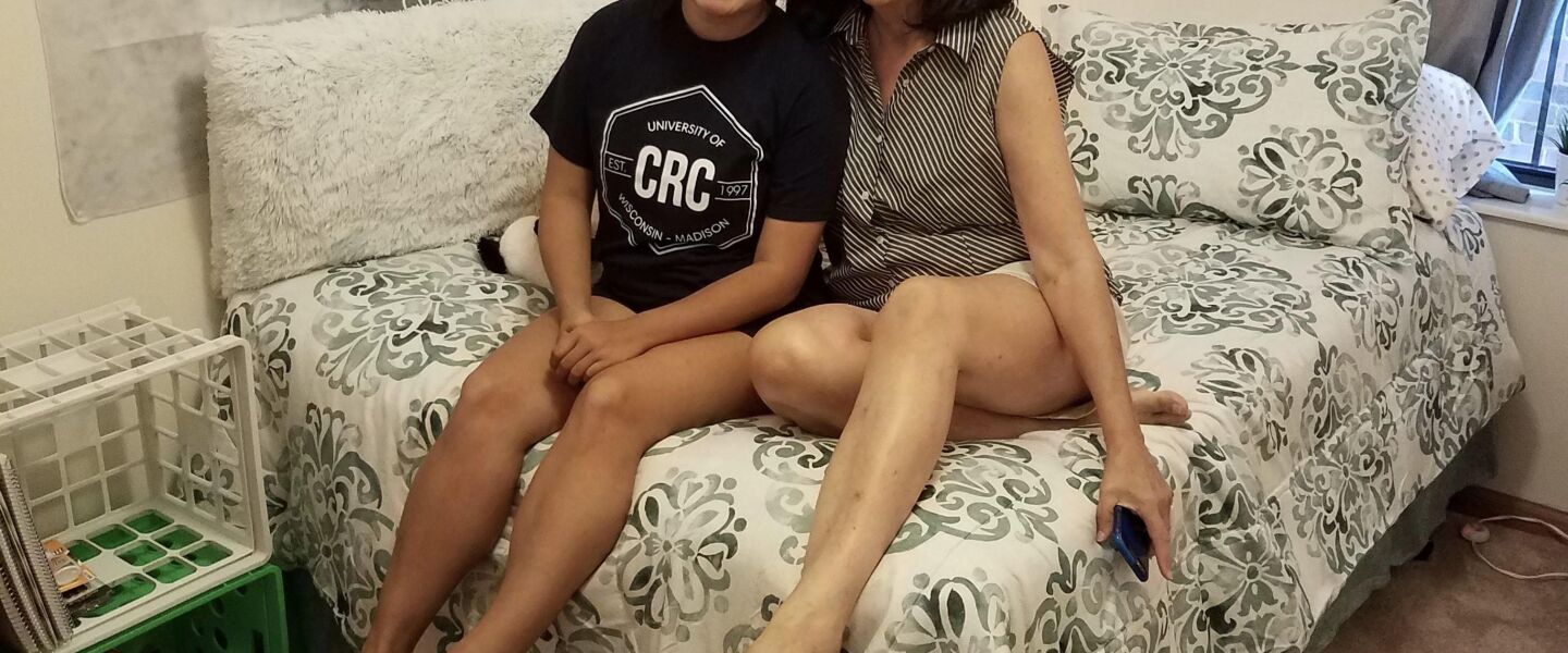 Laura Garbacz (right) and her daughter Ali, now grown up and seated on her dorm room bed.