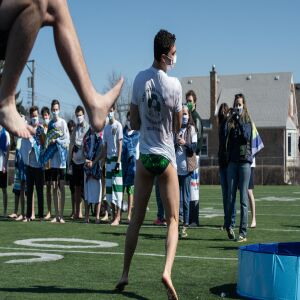 A student jumps into wading pool filled with snow and water while another runs for St. Patrick High School’s version of the Polar Plunge.