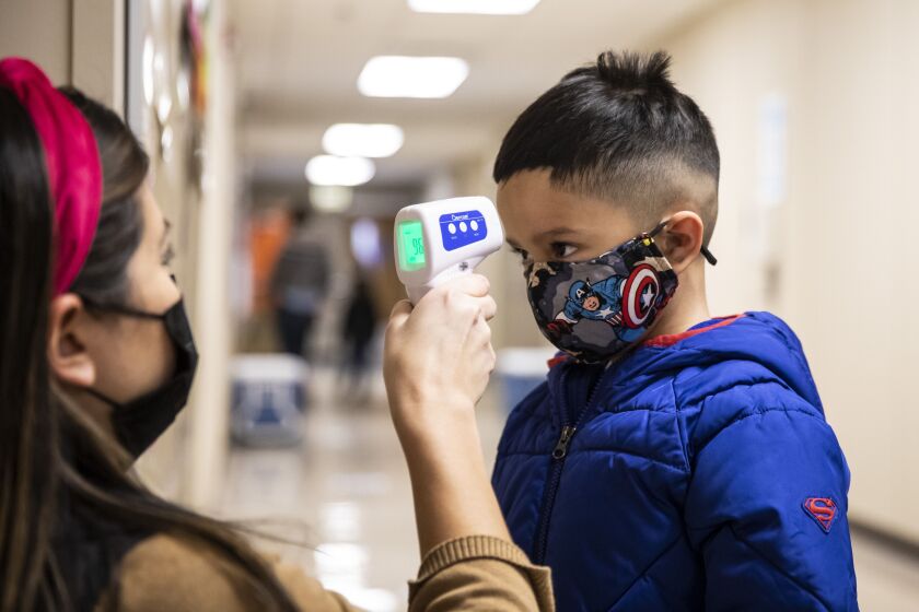 A preschool student gets his temperature checked as he walks into Dawes Elementary School in Chicago.