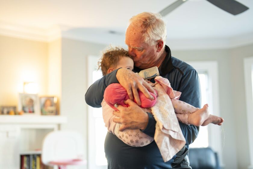 Stephen Helmer holds his granddaughter Caroline Costello in his daughter’s home in Skokie on Friday, one day after the CTA Yellow Line train he was riding crashed into a snowplow. He, his wife, his daughter and two grandkids were injured in the crash.