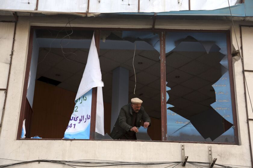 An Afghan shopkeeper removes the shuttered glasses of his shop in the aftermath of Saturday’s suicide attack in Kabul, Afghanistan, on Sunday. | AP photo