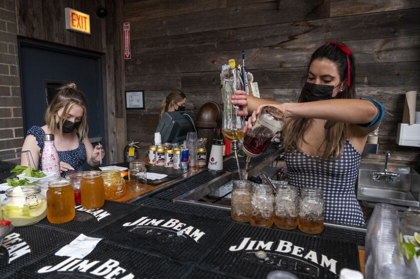 Two waitresses (left) go over orders as a bartender mixes drinks at the Old Crow Smokehouse in Wrigleyville on Friday, Sept. 3, 2021.