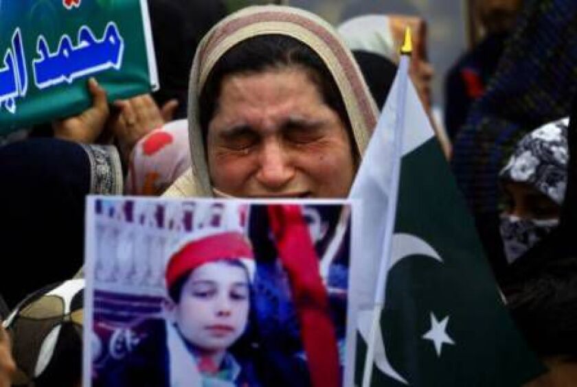 A mother weeps as she carries a picture of her slain son during a tribute to students who were killed in an attack on a school last year by Taliban gunmen, in Peshawar, Pakistan, Saturday, Feb. 7, 2015. (AP Photo/Mohammad Sajjad)