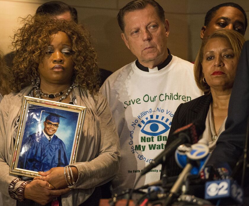 Alicia Idleburg holds a photo of her 20-year-old son, Dariel, a victim of gun violence. Rev. Michael Pfleger and Annette Nance-Holt, who lost her 16-year-old son Blair to gun-violence, were at a press conference Tuesday after a lawsuit was filed in Cook C