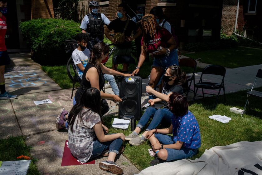 Youth activists demanding an end to police presence in Chicago Public Schools listen to a broadcast of the Chicago Board of Education meeting outside Board President Miguel del Valle’s home on June 24, 2020.