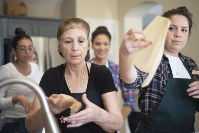 A few of Elodia Esquinca’s granddaughters crowd around her as she demonstrates how to make a tamale in Aurora on Dec. 16, 2018. | Colin Boyle/Sun-Times