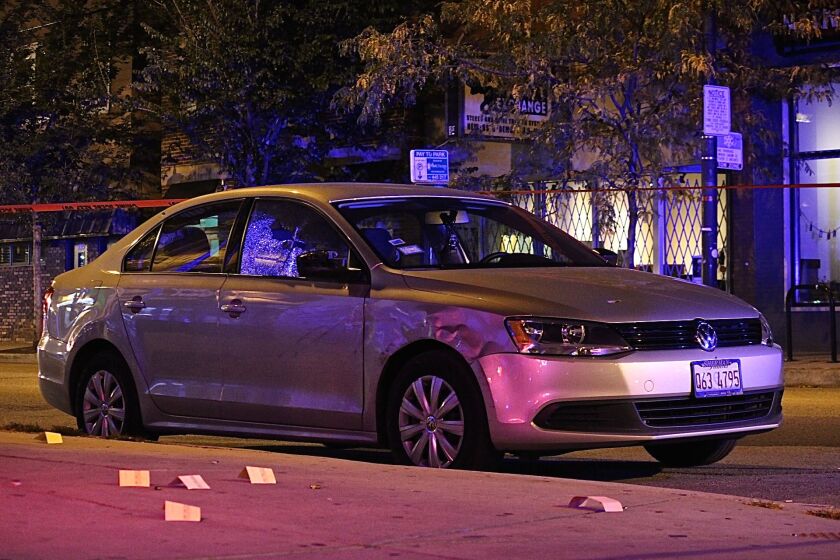 A silver Volkswagen surrounded by shell casings is parked inside the crime scene tape early Saturday. | Daniel Brown/Sun-Times