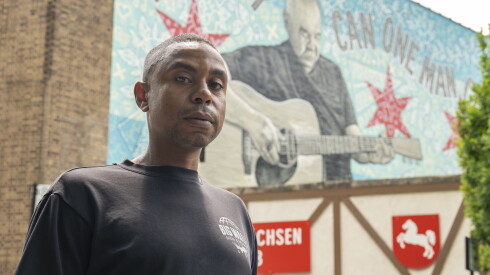 Darius Dennis stands near the John Prine mural in Lincoln Square.