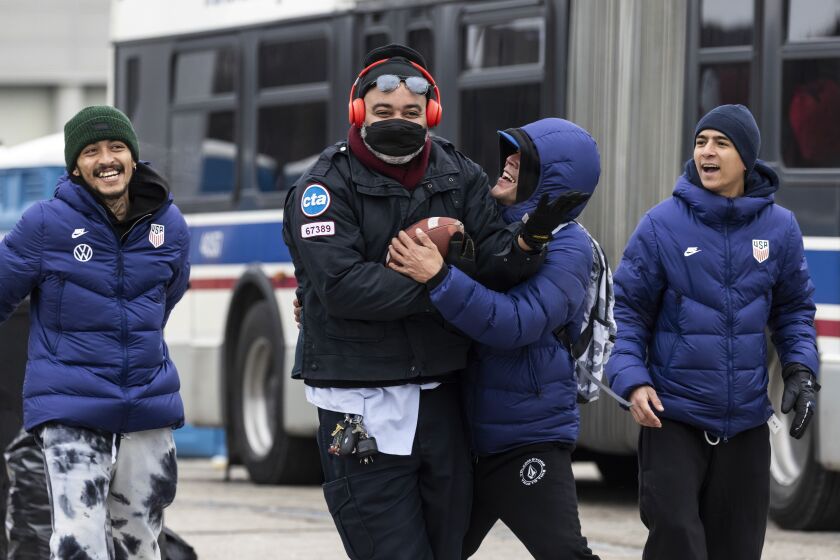 A Chicago Transit Authority bus driver plays football with asylum seekers at Chicago’s designated landing zone for new migrant arrivals at 800 S. Desplaines St. in the West Loop, Wednesday, Jan. 10.