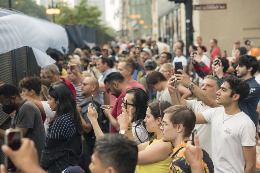Fans hold up their phones to record cars racing by near Michigan and Harrison St during the Xfinity Series Nascar The Loop 121 Race, Saturday, July 1, 2023.