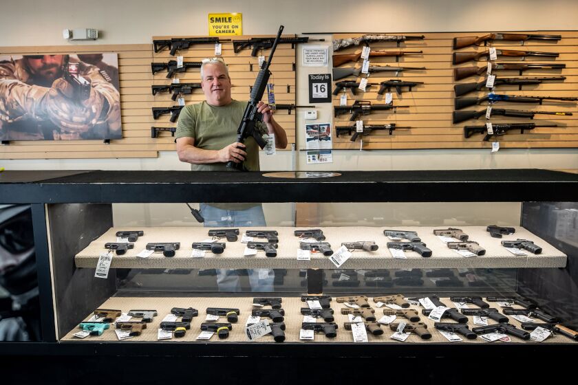 Robert Bevis, owner of Law Weapons & Supply in Naperville, holds an AR-15 rifle. He says many of his customers want firearms and extended-capacity magazines for protection.