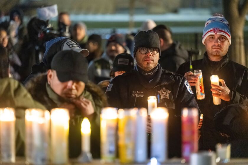 Un officier de police de Chicago attend son tour jeudi pour placer une bougie sur un mémorial dédié à l'officier Andres Vasquez Lasso à Hale Park.