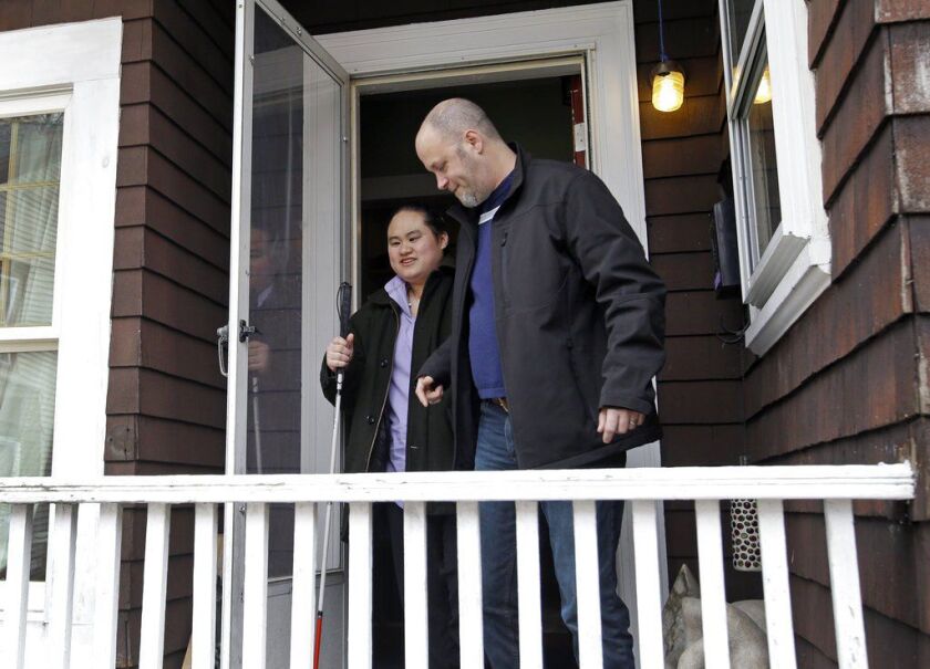 Wil Darcangelo helps his 22-year-old adopted daughter, Lavender, who is blind and autistic, leave their home in Fitchburg, Mass. (AP Photo/Elise Amendola)