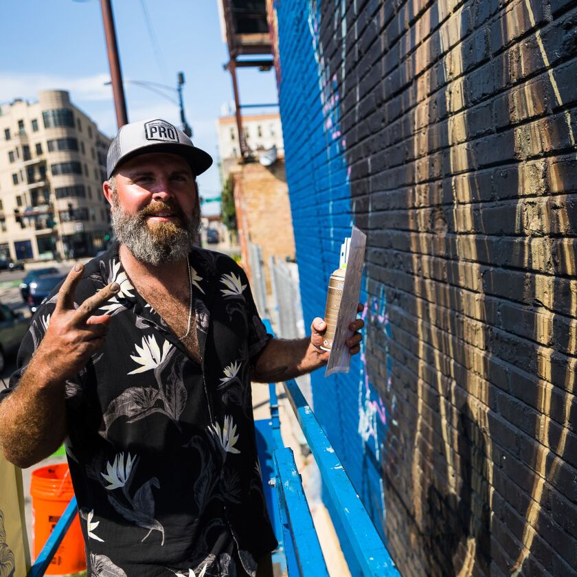 Thomas Turner takes a break from painting his side of the mural at 488 N. Milwaukee Ave.