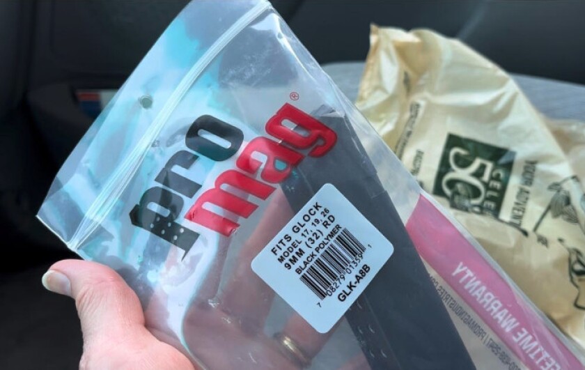 A hand holding a 32-round magazine still in its plastic packaging, with a store plastic bag in the background. A Chicago Sun-Times reporter bought the extended-capacity magazine in Hammond, Indiana, just across the state line from Chicago and Cook County, where such magazines are banned.