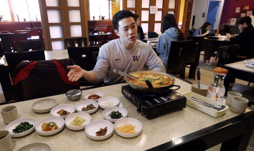 Server Young Kim talks about the South Korean dish called budae jjigae, or “army stew,” he is serving simmering atop a heating plate at a Korean restaurant in Shoreline, Wash. | Elaine Thompson