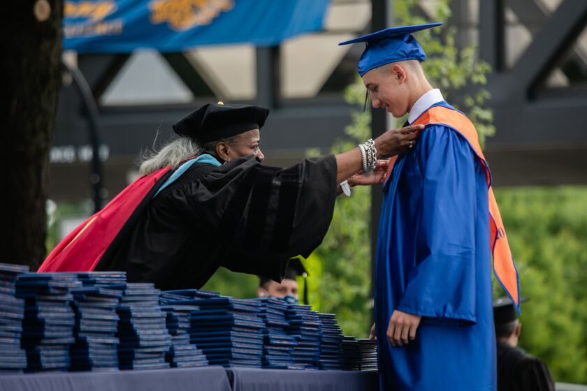 Joyce Kenner, the principal of Whitney Young Magnet High School fixes Matthew Burzec’s gown during the Whitney Young Magnet High School graduation on June 13, 2020.