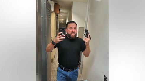 U.S. Customs and Border Protection Officer Luis Uribe holds a gun and poses in a photo.