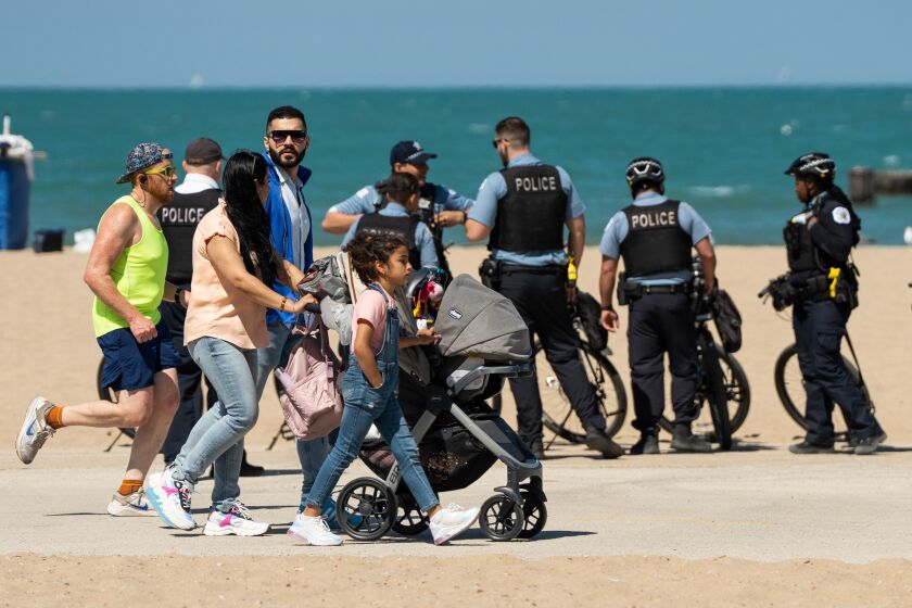 A family walks in front of police officers after a group of teenagers got into a fight and shots were fired, according to a Chicago Police Department spokesperson, ahead of Memorial Day weekend at North Avenue Beach, Friday, May 26, 2023. No one was injured and one individual is in custody, according to police. | Pat Nabong/Sun-Times