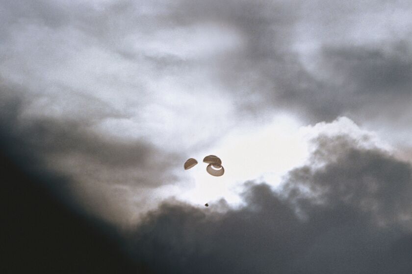 In this April 17, 1970 photo made available by NASA, the command module carrying the Apollo 13 crew parachutes to a splashdown in the Pacific Ocean.