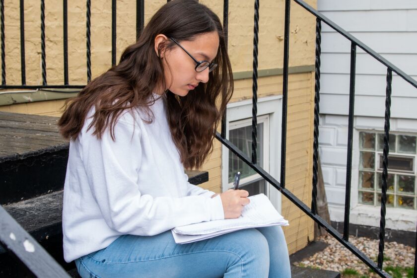 Marlenne Garcia does school work Friday on the steps of her McKinley Park home.