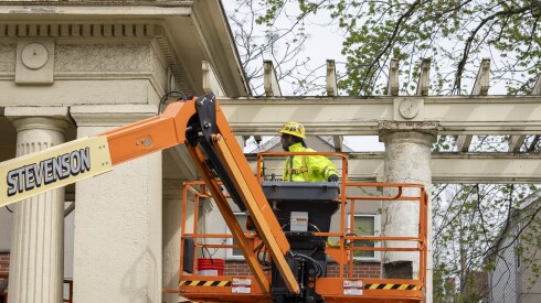 A worker on a lift inspects the trellis and west portico of the pergola at Sears Sunken Garden.