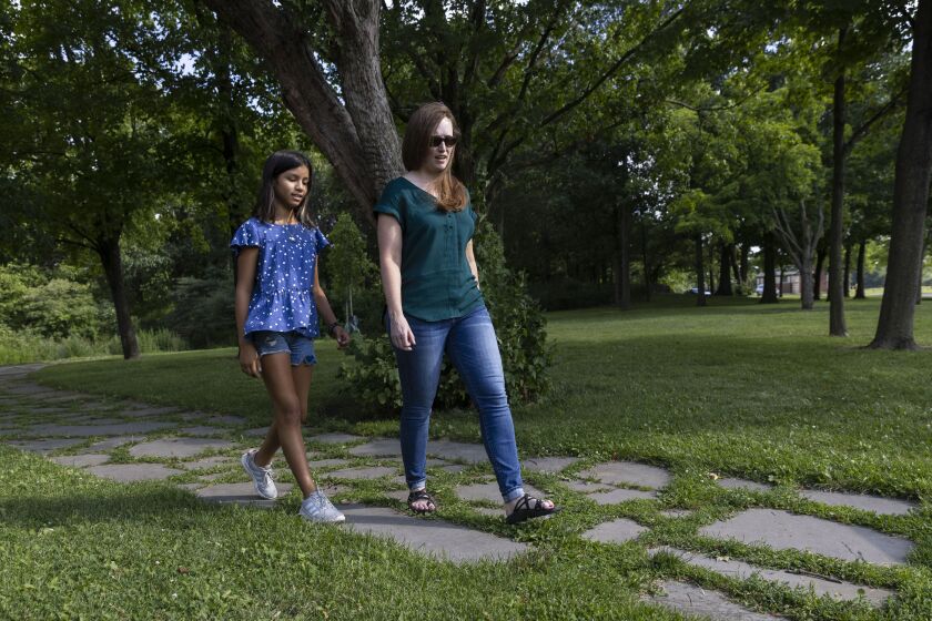 Melissa Zammit (right) and Mia Naranjo Vera chat Thursday as they walk on a trail at Columbus Park in Austin.