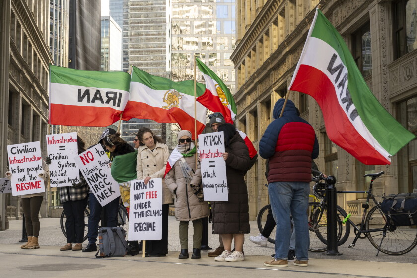 A group of protesters holding Iranian flags stands on a street in Chicago.