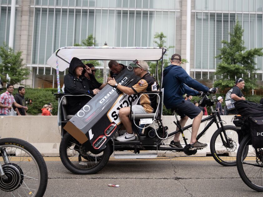 Fans of the Huck’s #1 NASCAR race team ride in a pedi-cab while carrying the detach bumper of the Huck’s car, which was lost during the qualifying round of The Loop 121 NASCAR Chicago Street Race on Saturday, July 1, 2023 in Chicago.