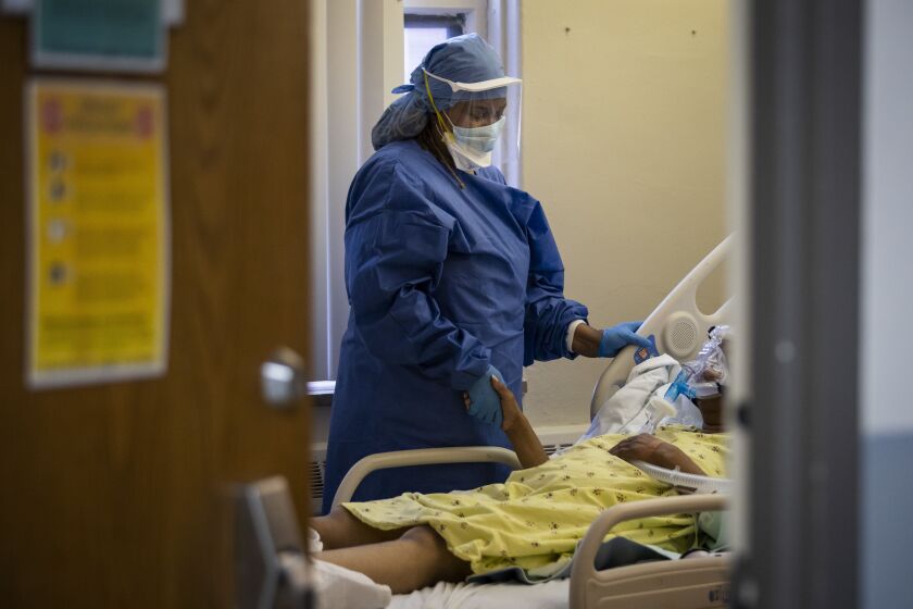 In 2020, Nurse Jeanette Averett comforts a 56-year-old woman suffering from COVID-19 who was struggling with anxiety because of her non-invasive ventilator at Roseland Community Hospital on the Far South Side. “COVID has taken a terrible toll on the health and well-being of our city’s residents particularly those who are Black and Latinx,” Mayor Lori Lightfoot said Monday in a statement.