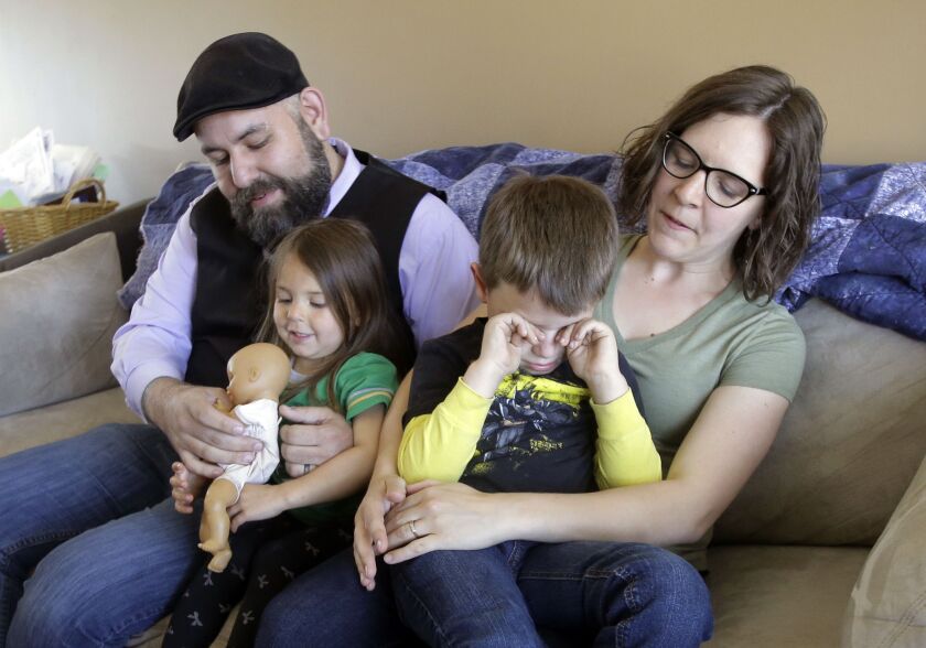 Jake Martinez, who has epilepsy, holds his daughter Jenny, while his wife Kat, holds their son Joe, at their home in Murray, Utah. Martinez said Obamacare made it possible to get affordable coverage for himself, his wife and their children. Without it, he