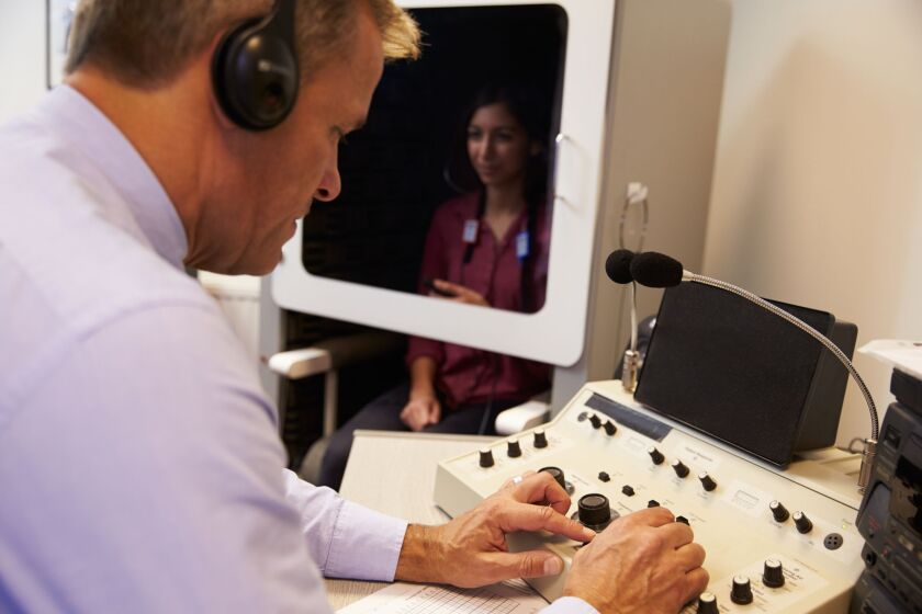 An audiologist conducts a hearing test. | THINKSTOCKIMAGES